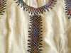 White, sleeveless traditional Ethiopian dress with multicolored cross embroidered motif