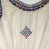 White, sleeveless traditional Ethiopian dress with multicolored cross embroidered motif